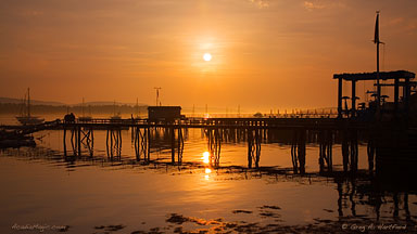 Southwest Harbor, Maine golden sunrise with long dock in silhouette